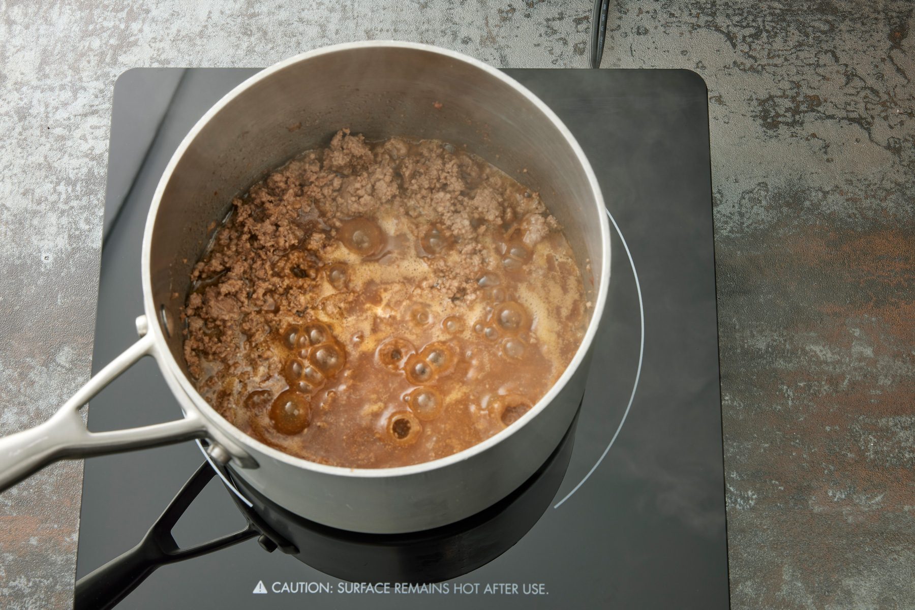 High angle view shot of cook and stir for 2 minutes; induction; dark texture surface