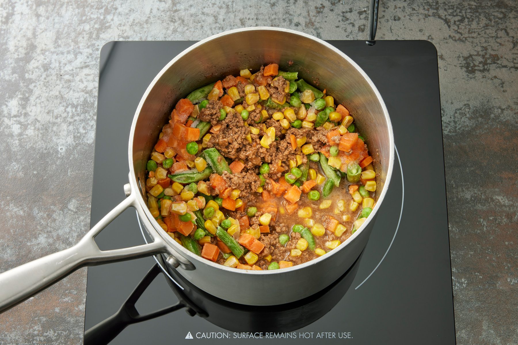 Overhead shot of the same sauecapn; add vegetables; cook and stir for 5 minutes; stir in half the onions and cheese; induction; dark texture surface