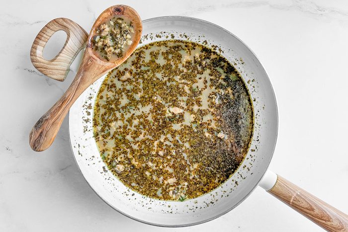 Sauce for Taste of Home Linguine with Clam Sauce in a white skillet with wooden spoon on a marble surface
