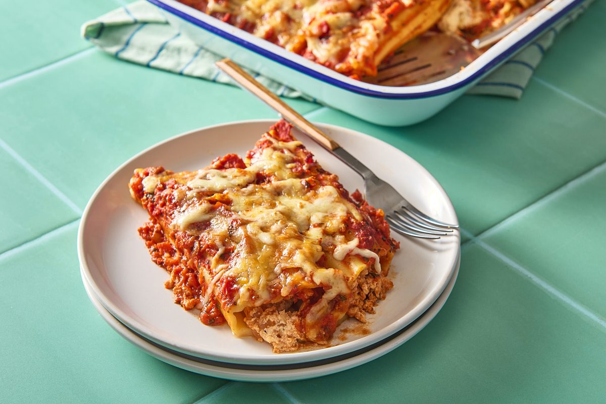 Closeup shot of a portion of cheese manicotti on a plate with the baking tray in the background