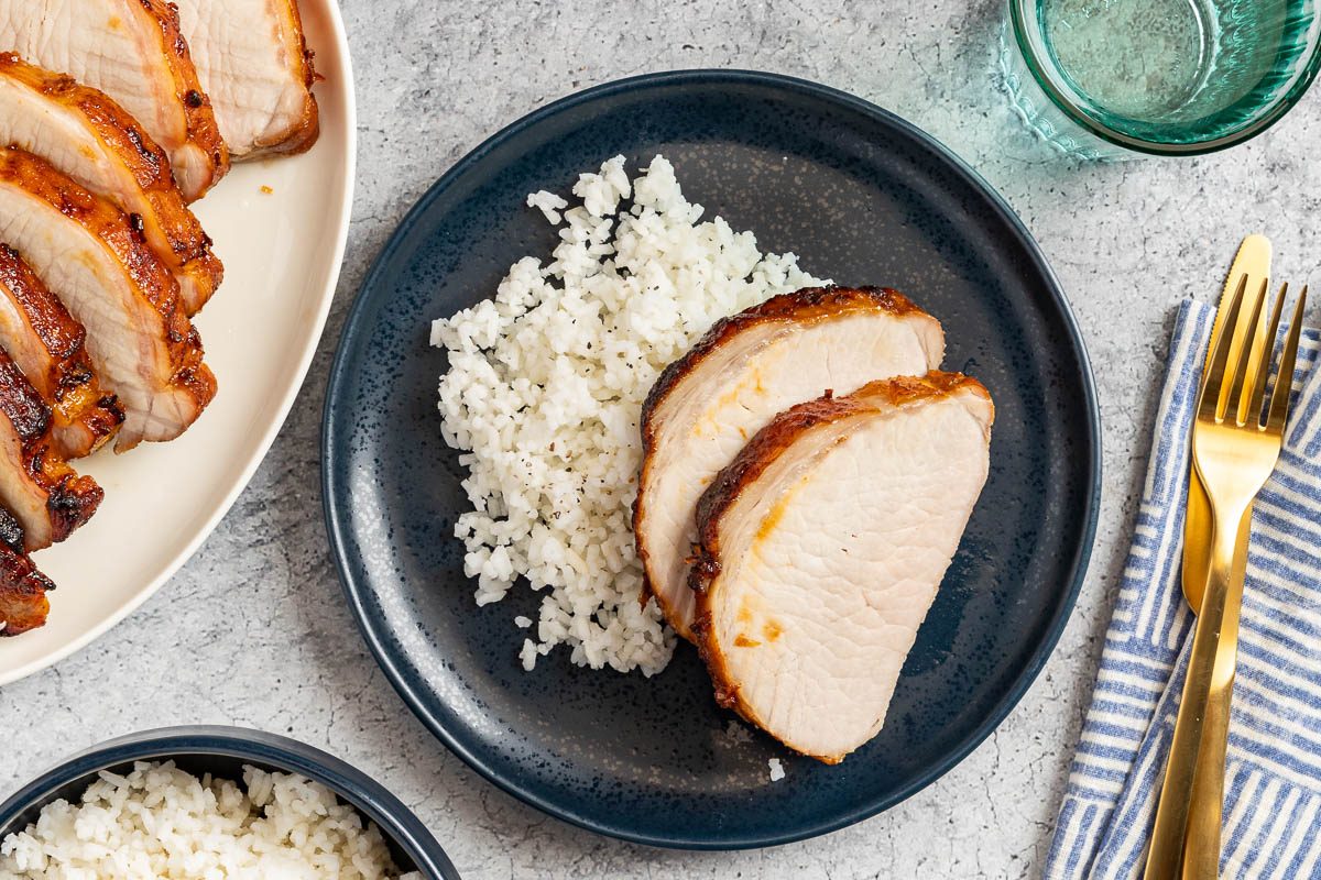 Taste of Home Marinated Pork Loin photo of the finished recipe cut into slices and served on plates with a side of rice.