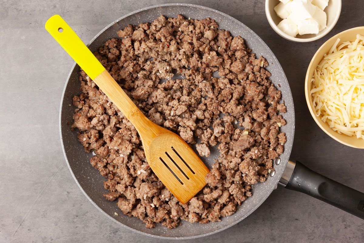 Step 2 of Taste of Home Meaty Manicotti is to cook the sausage and beef until the meat is no longer pink. Add the garlic, and cook for one minute longer. Remove the pan from the heat and drain the meat, then let it cool for 10 minutes.