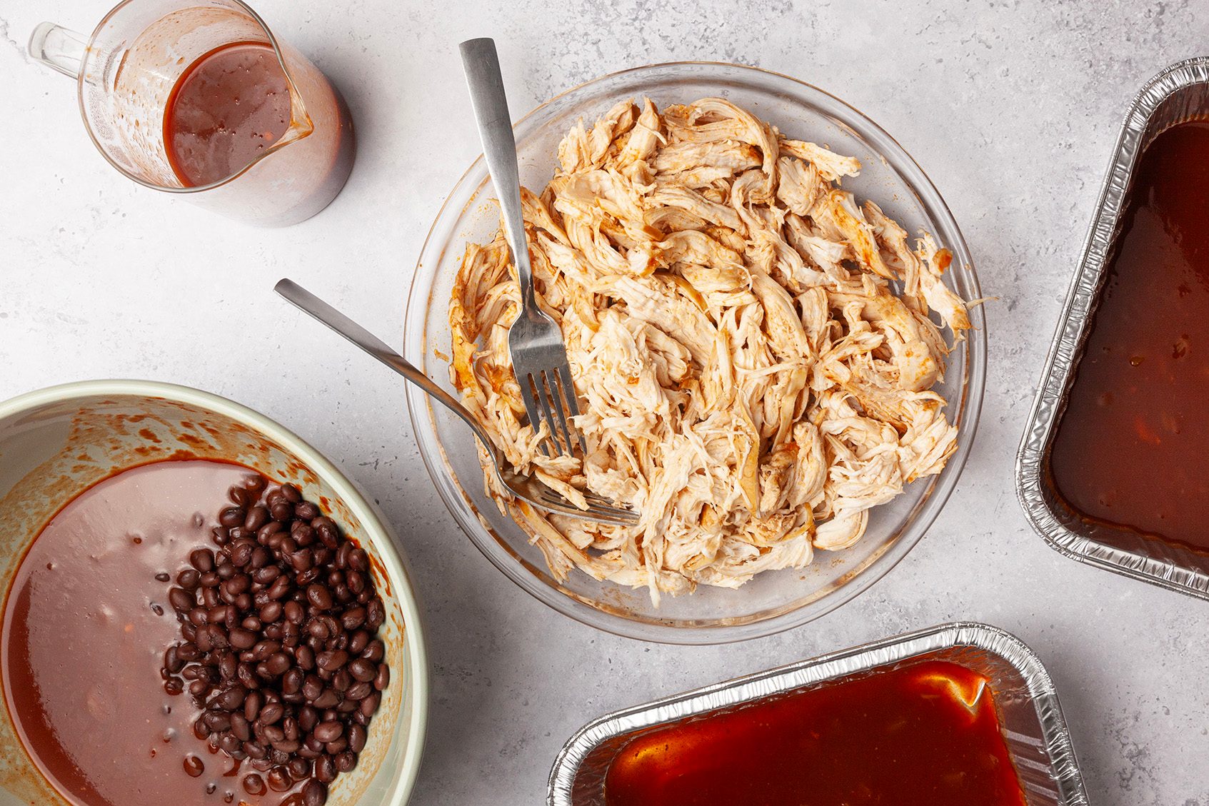 Step 2 of Taste of Home Crock-Pot Chicken Enchiladas is to remove chicken and shred with two forks. Reserve 1-2/3 cups cooking juices. Pour the remaining cooking juices into a large bowl; add the beans and shredded chicken. Coat two freezer-safe 8-inch square baking dishes with cooking spray; add 1/2 cup of the reserved juices to each.