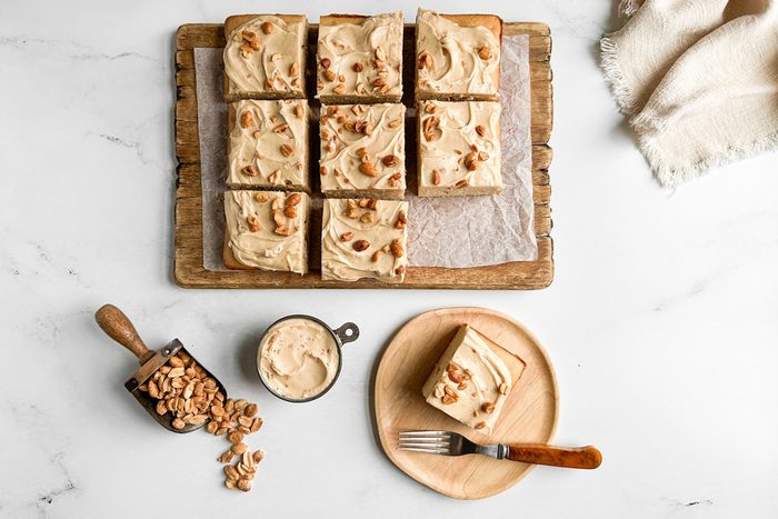 Taste of Home Peanut Butter Cake on wooden board and plate on a marble surface