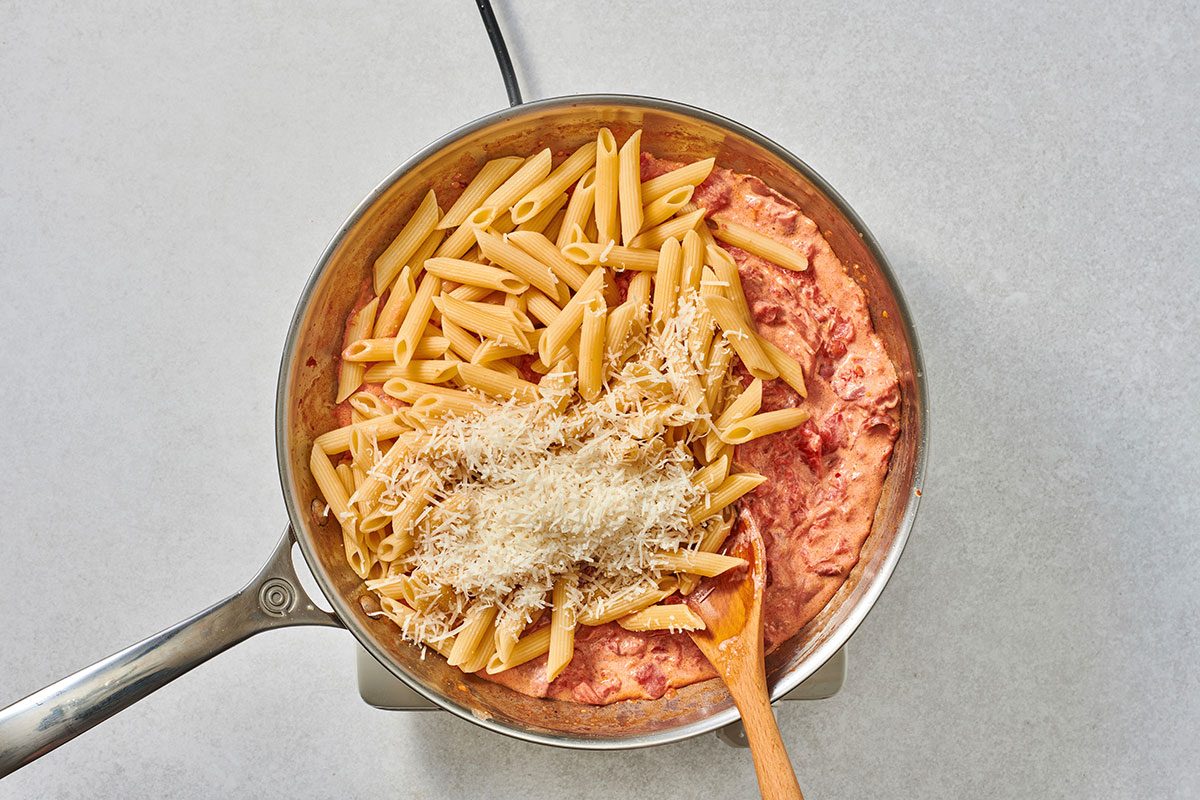 Adding Parmesan and pasta to the vodka sauce