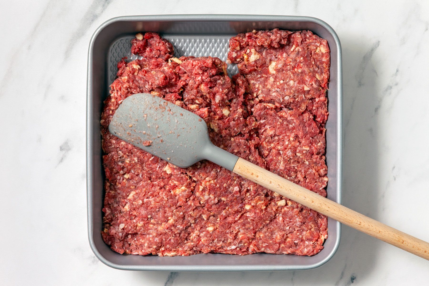 Beef and cracker crumb mixture in a square pan