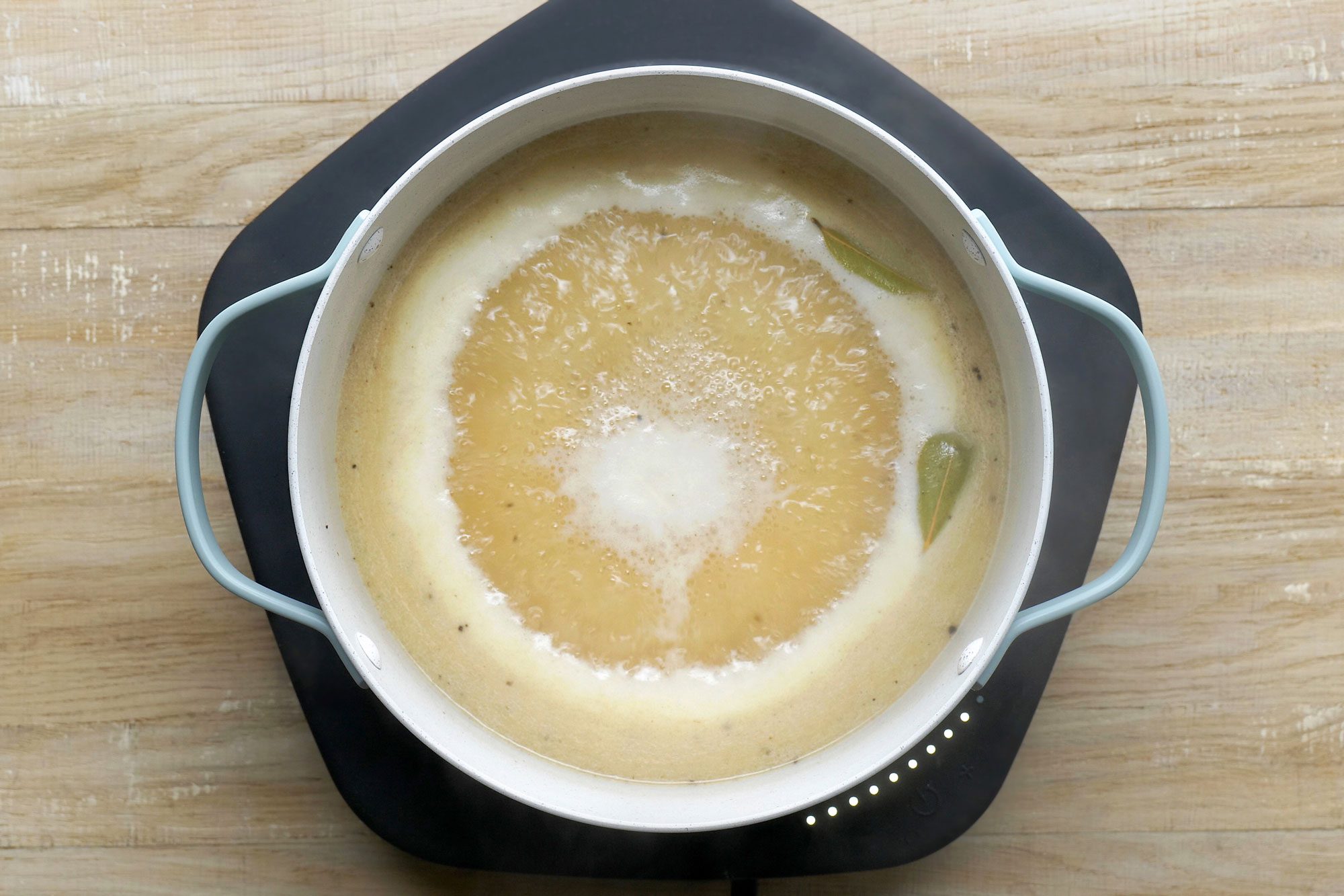 overhead shot; wooden background; added in broth, Stir in the bay leaves, salt, pepper, pepper sauce, Worcestershire sauce and nutmeg and boiling;