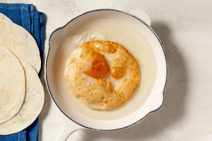 Tortilla being heated in a skillet.