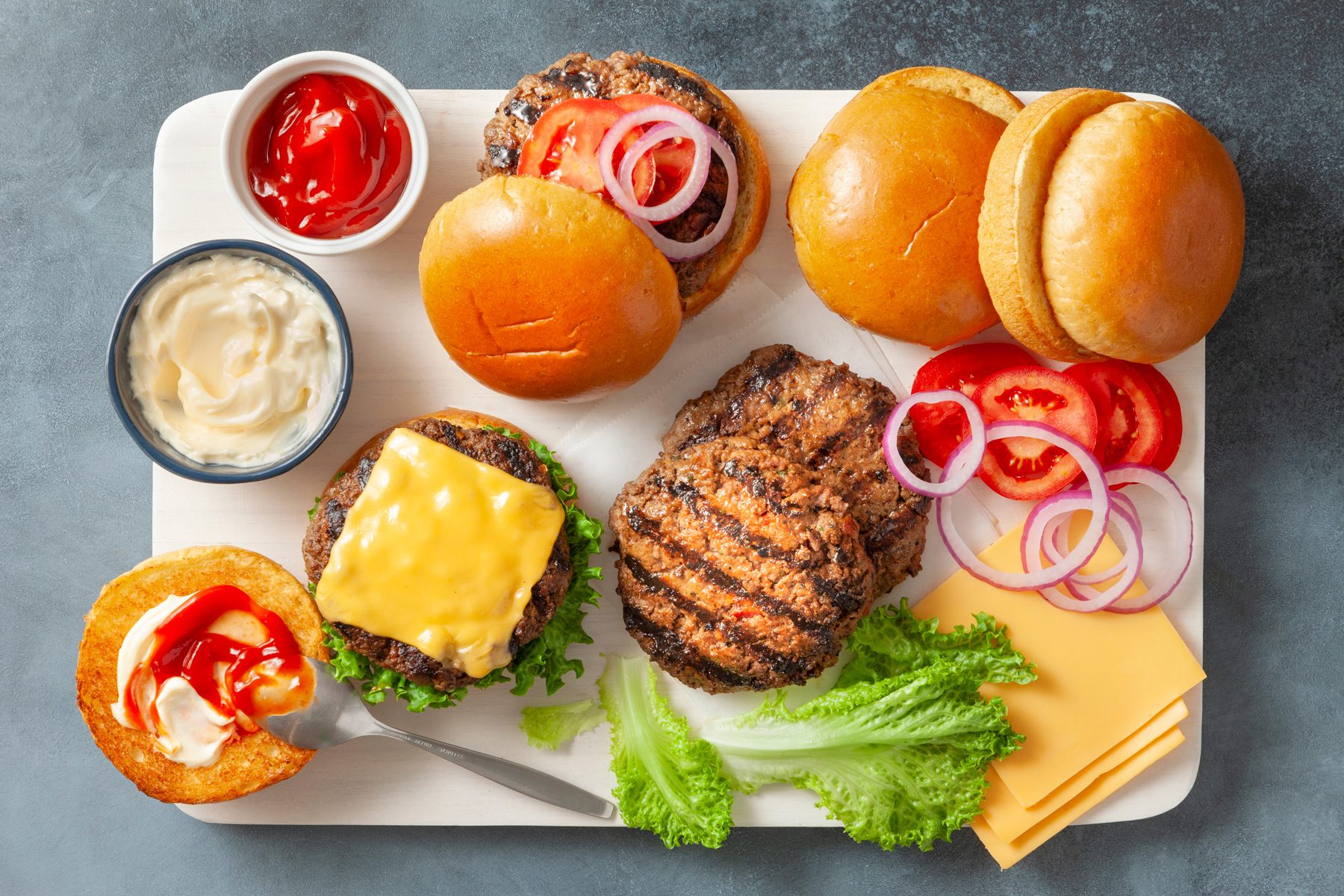 overhead shot of grilled patties, buns, sauces and vegies