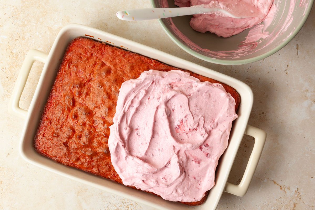 Step 4 of Taste of Home Raspberry Cake is to spread the frosting evenly over it.