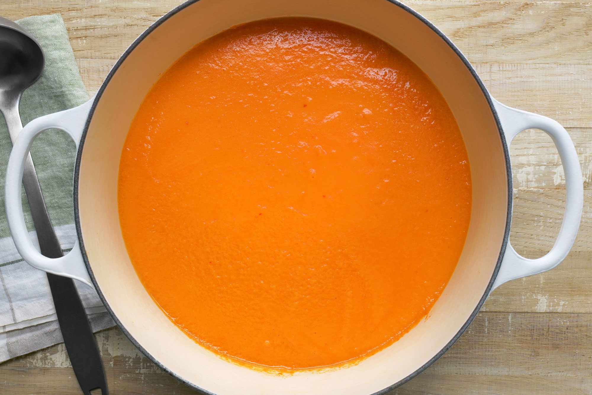 overhead shot of toasted tomato soup in a large bowl; Wooden Background;