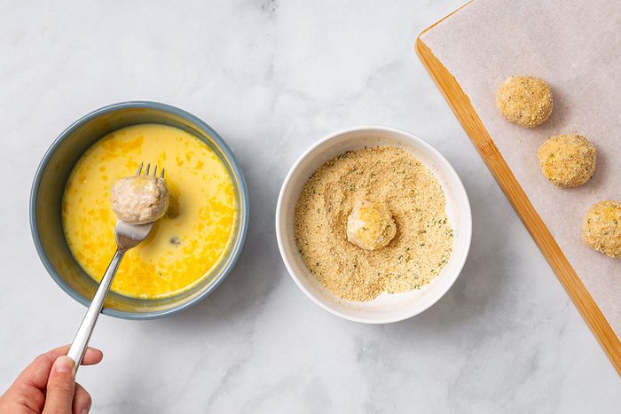 Sauerkraut balls being dipped in eggs then covered in breadcrumbs for step 5 for Sauerkraut Balls recipe for Taste of Home