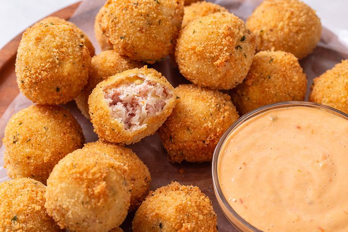 Sauerkraut Balls on a plate with dipping sauce for Sauerkraut Ball recipe for Taste of Home