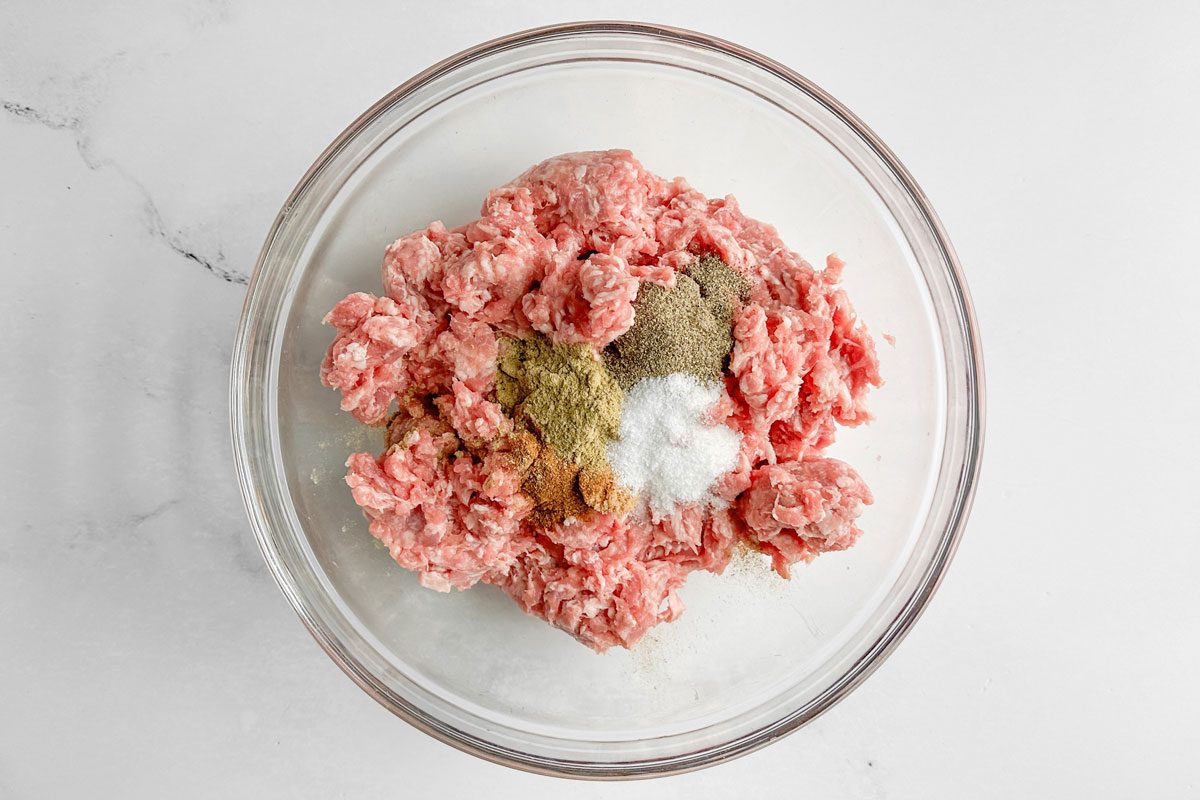 Ingredients for Taste of Home Sausage Patties in a glass bowl on a marble surface