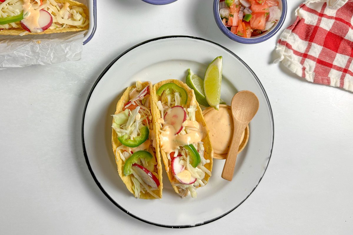 Taste of Home Shredded Chicken Tacos with assorted toppings on enamel dishes