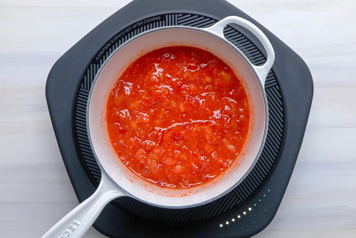 Overhead shot of measure 4-1/2 cups berries into a large saucepan; stir in pectin and bring to a rolling boil over high heat; stirring frequently; induction; wooden surface