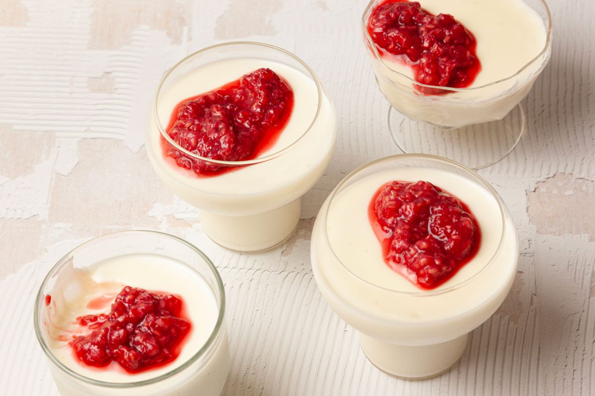 Four single servings of Taste of Home Swedish Creme garnished with mashed raspberries in glass dessert dishes