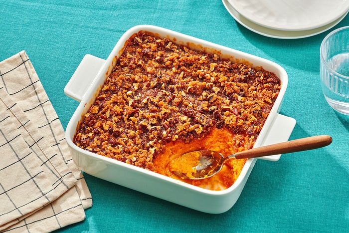 Sweet potato souffle with pecans in a baking dish with a portion removed and a serving spoon in the dish