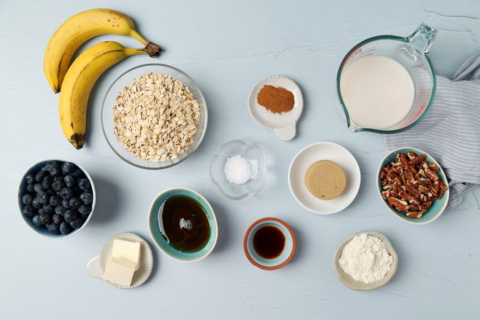 Ingredients for Taste of Home's Blueberry Baked Oatmeal in small dishes on a light blue surface.