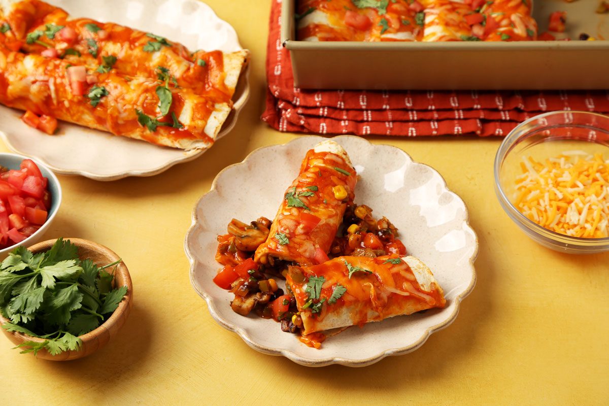 Close up of Taste of Home's Vegetarian Enchiladas served on a beige plate on a yellow surface.