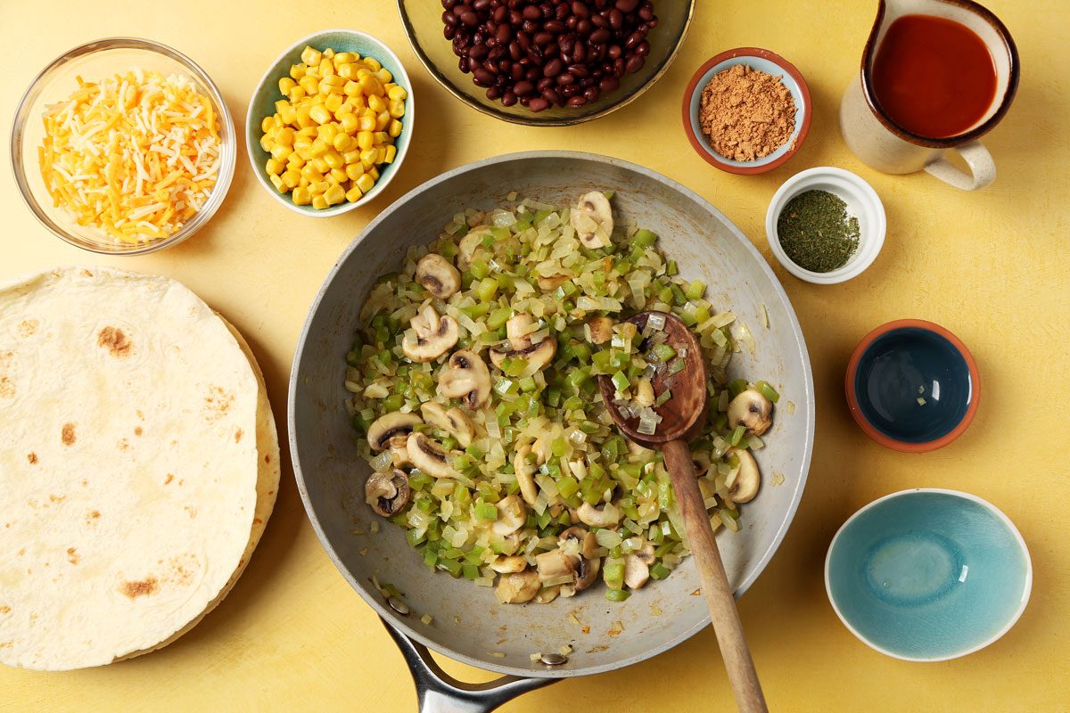 Making Taste of Home's Vegetarian Enchiladas with different ingredients laid out on a yellow surface.