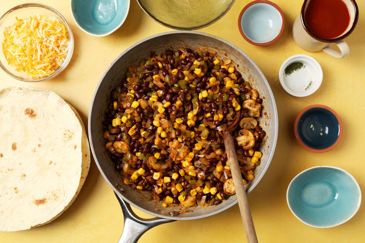 Making Taste of Home's Vegetarian Enchiladas with different ingredients laid out on a yellow surface.