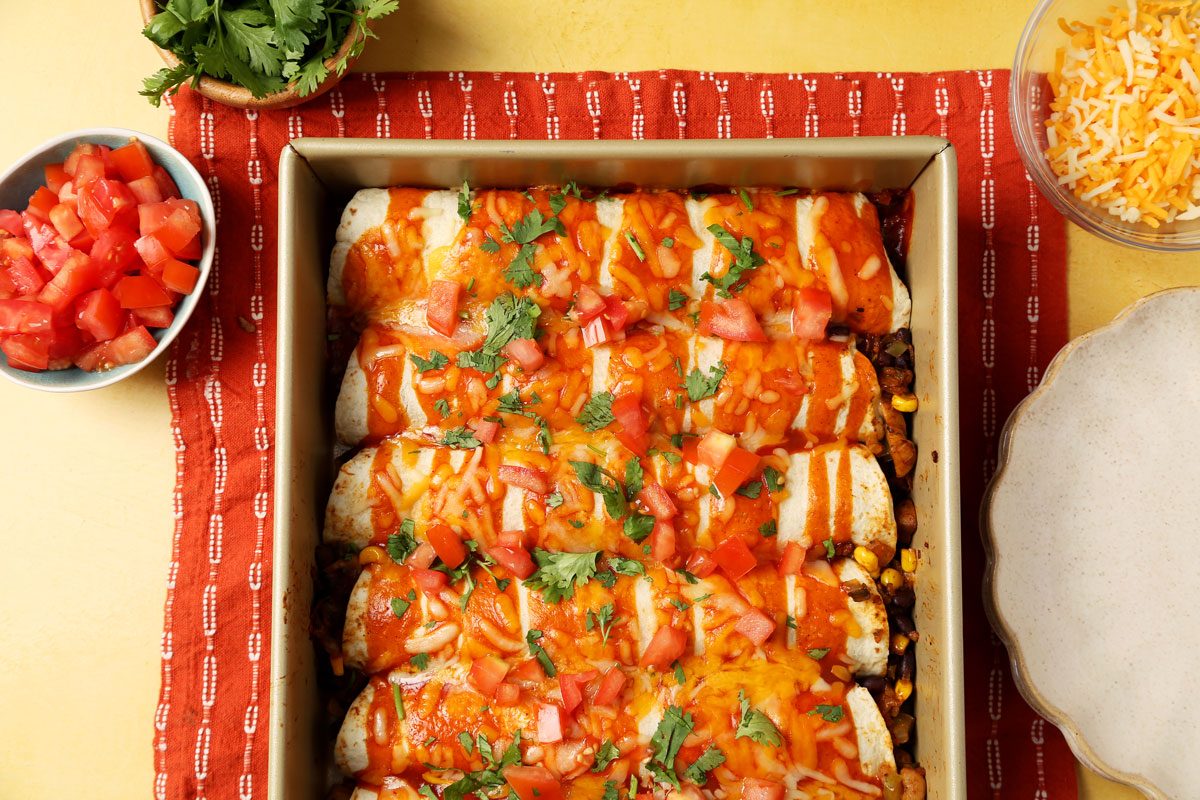 Close up of Taste of Home's Vegetarian Enchiladas served on a beige plate on a yellow surface.