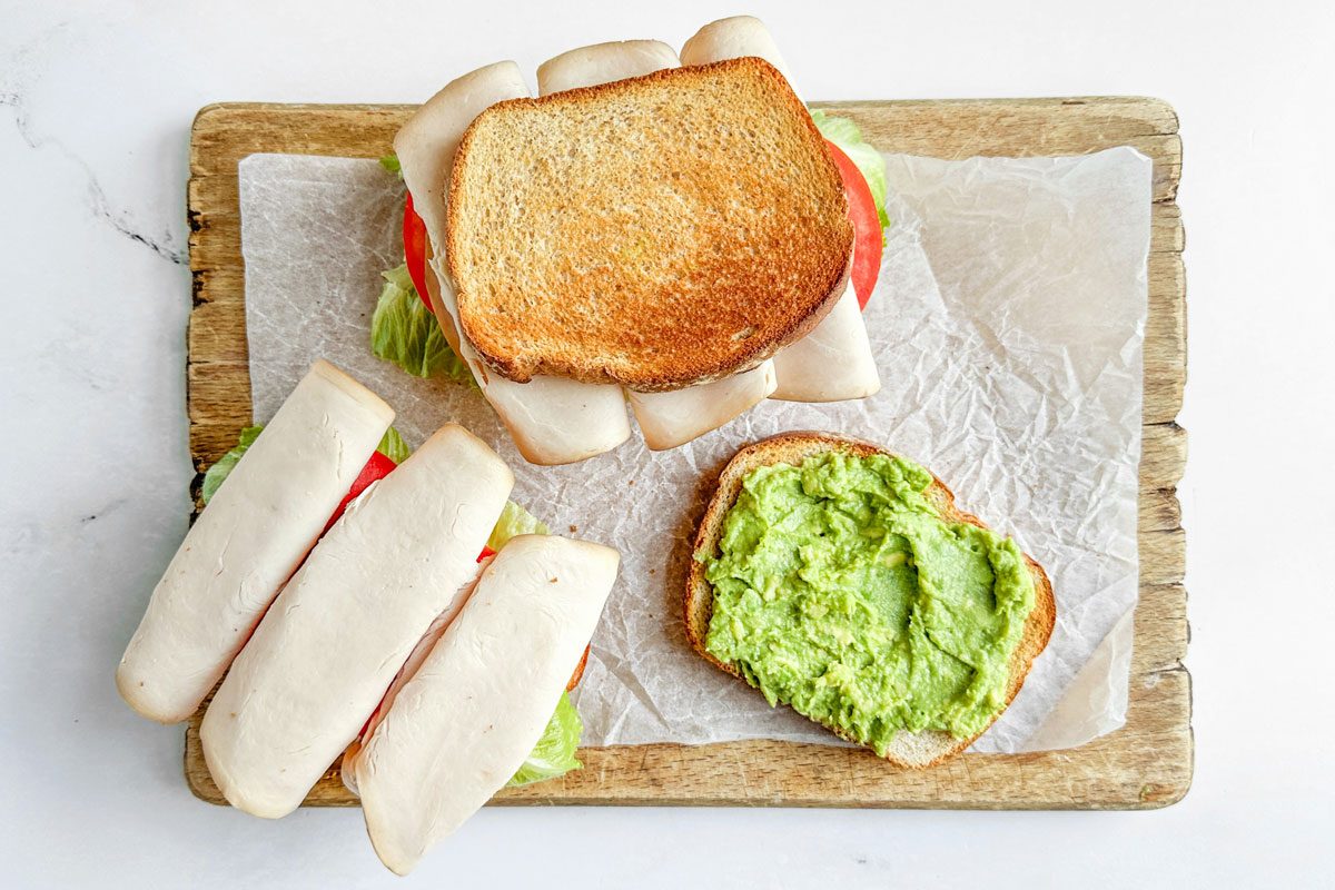 Taste of Home Turkey Avocado Sandwiches on a parchment lined wooden board