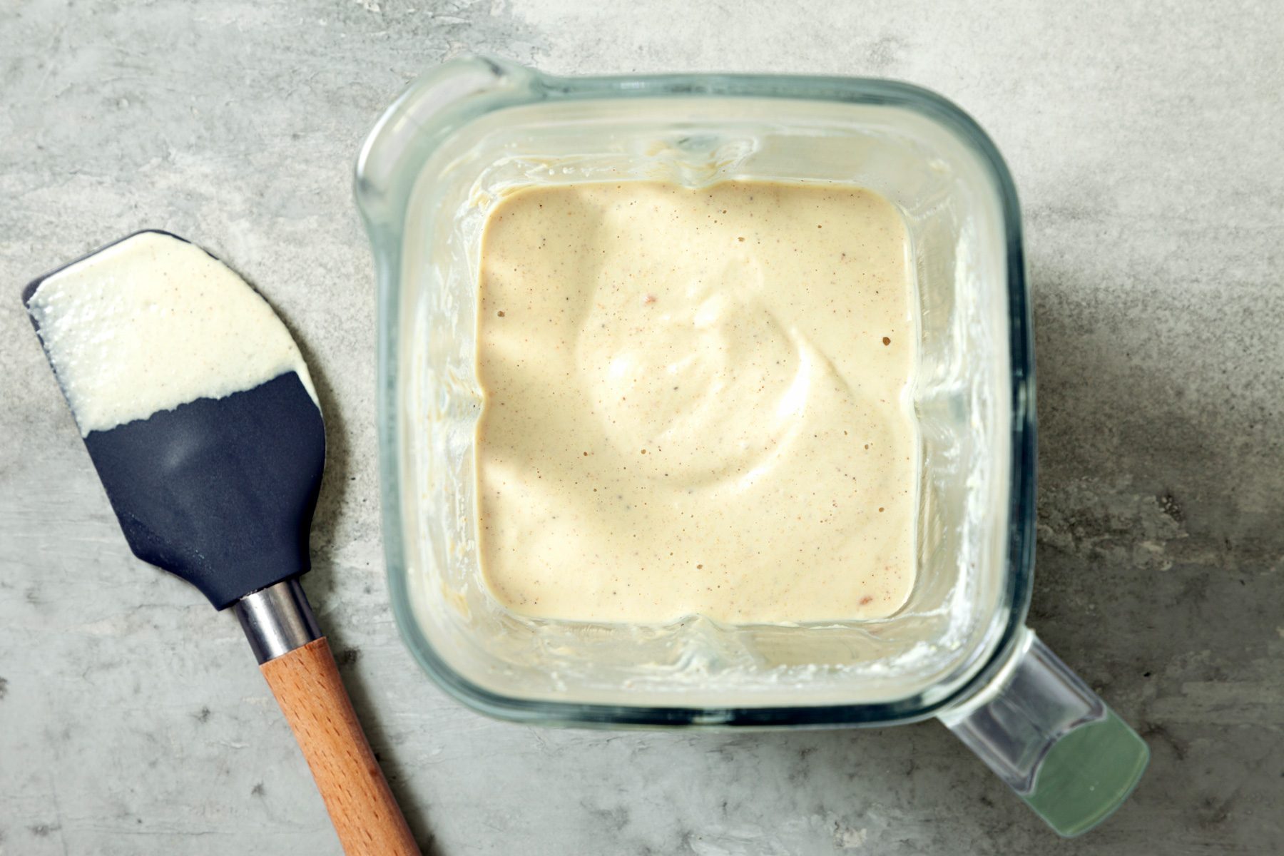 Overhead shot of blender; puree until smooth; spatula; grey marble surface