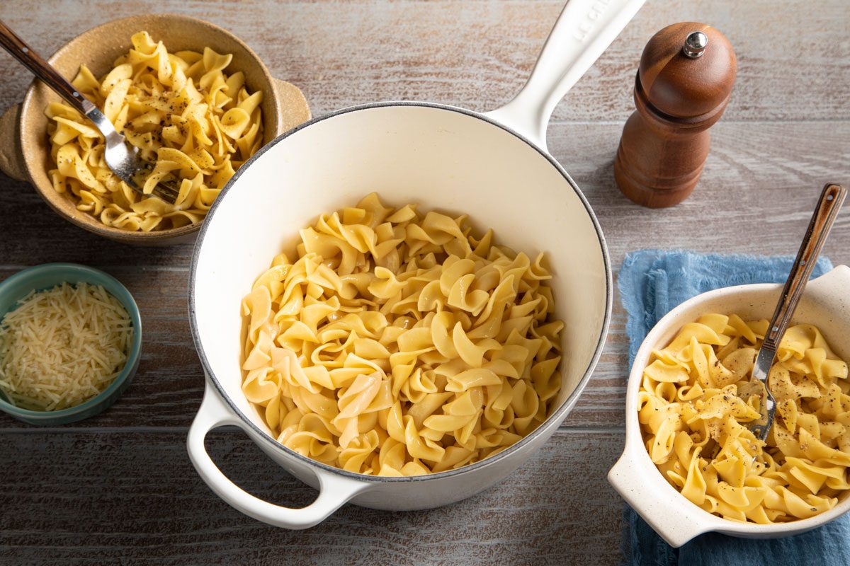Amish Noodles in a pot on a table with bowls of noodles nearby