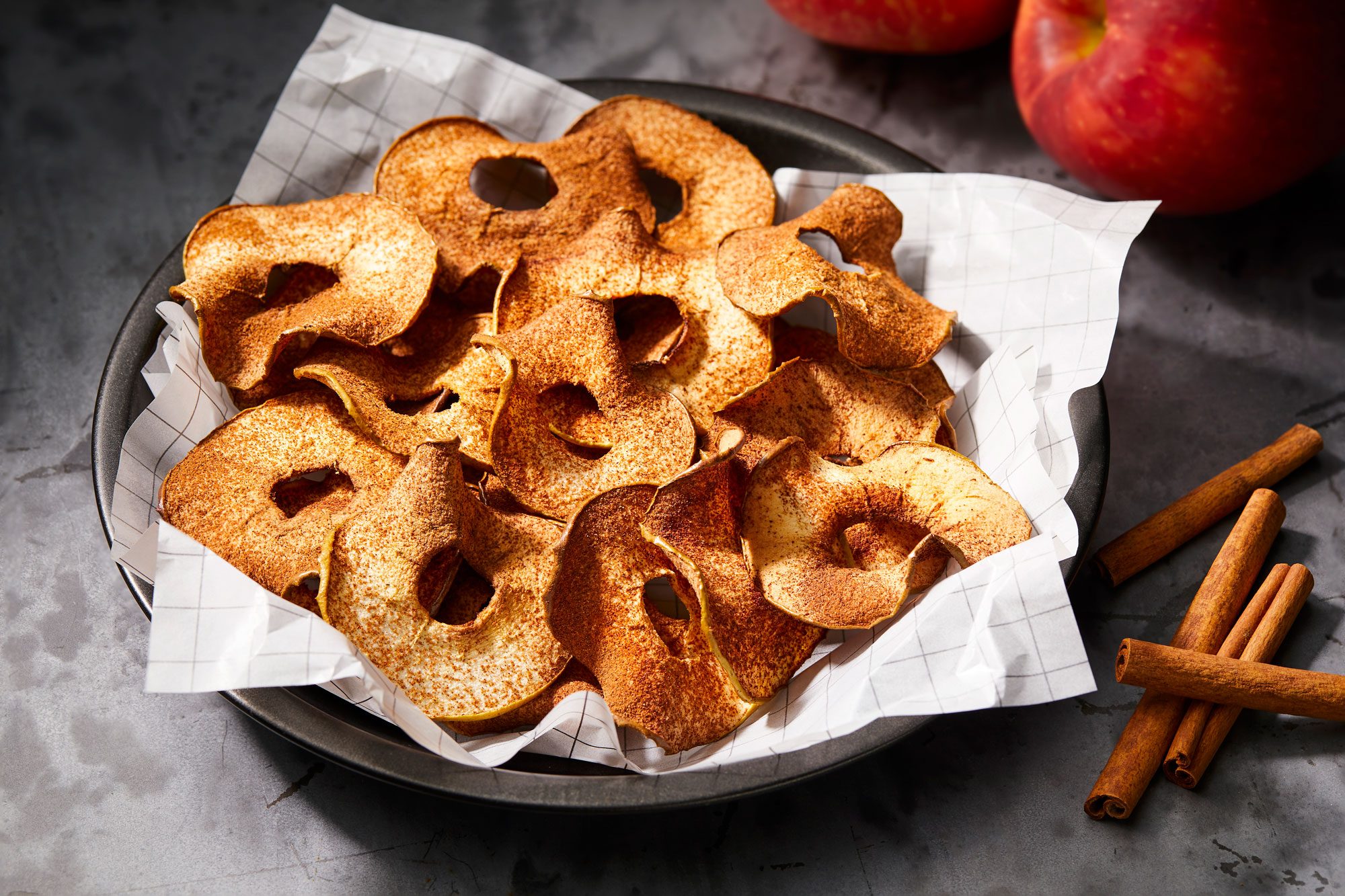 Apple Chips arranged on a piece of parchment paper and sprinkled with cinnamon