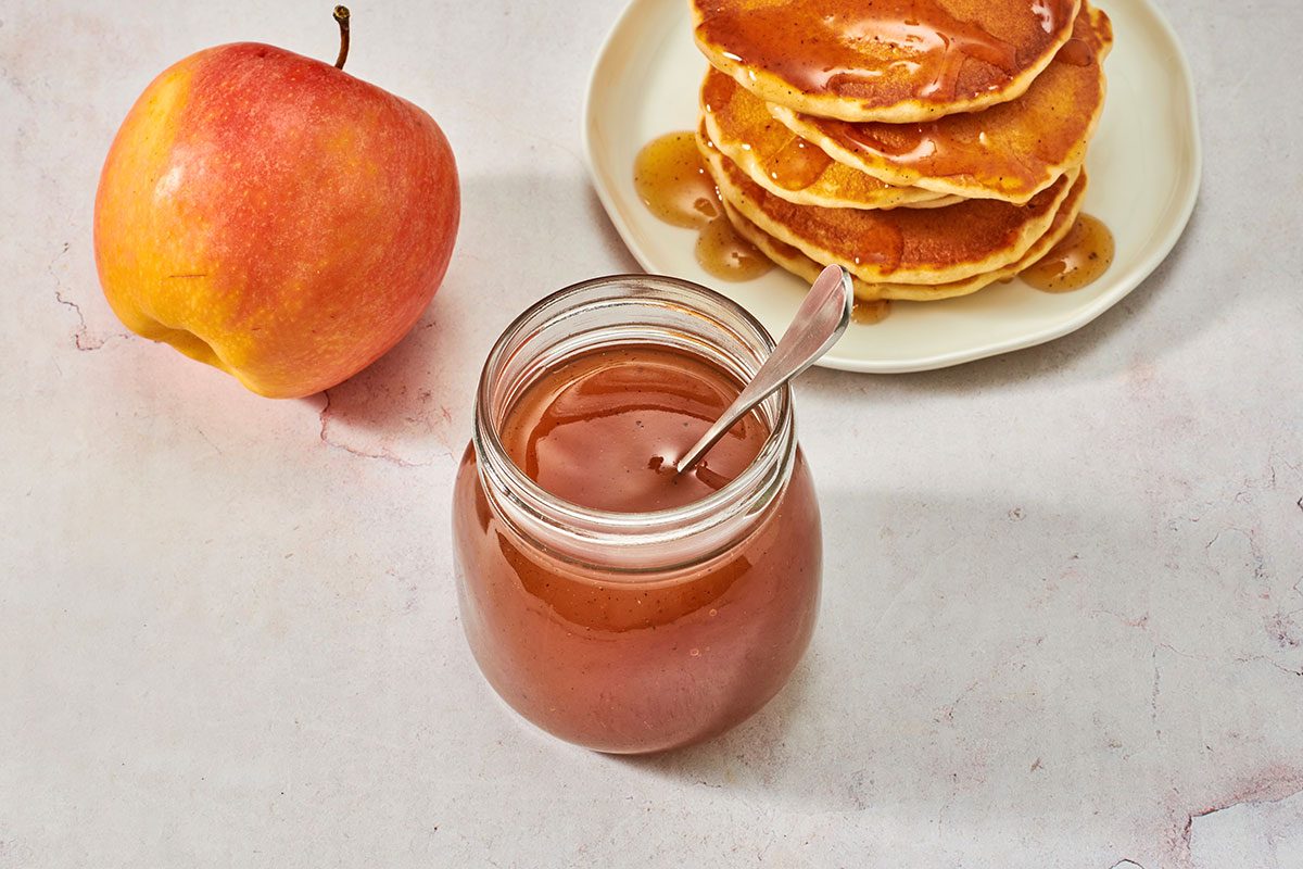 Syrup in a jar with a stack of pancakes in the background