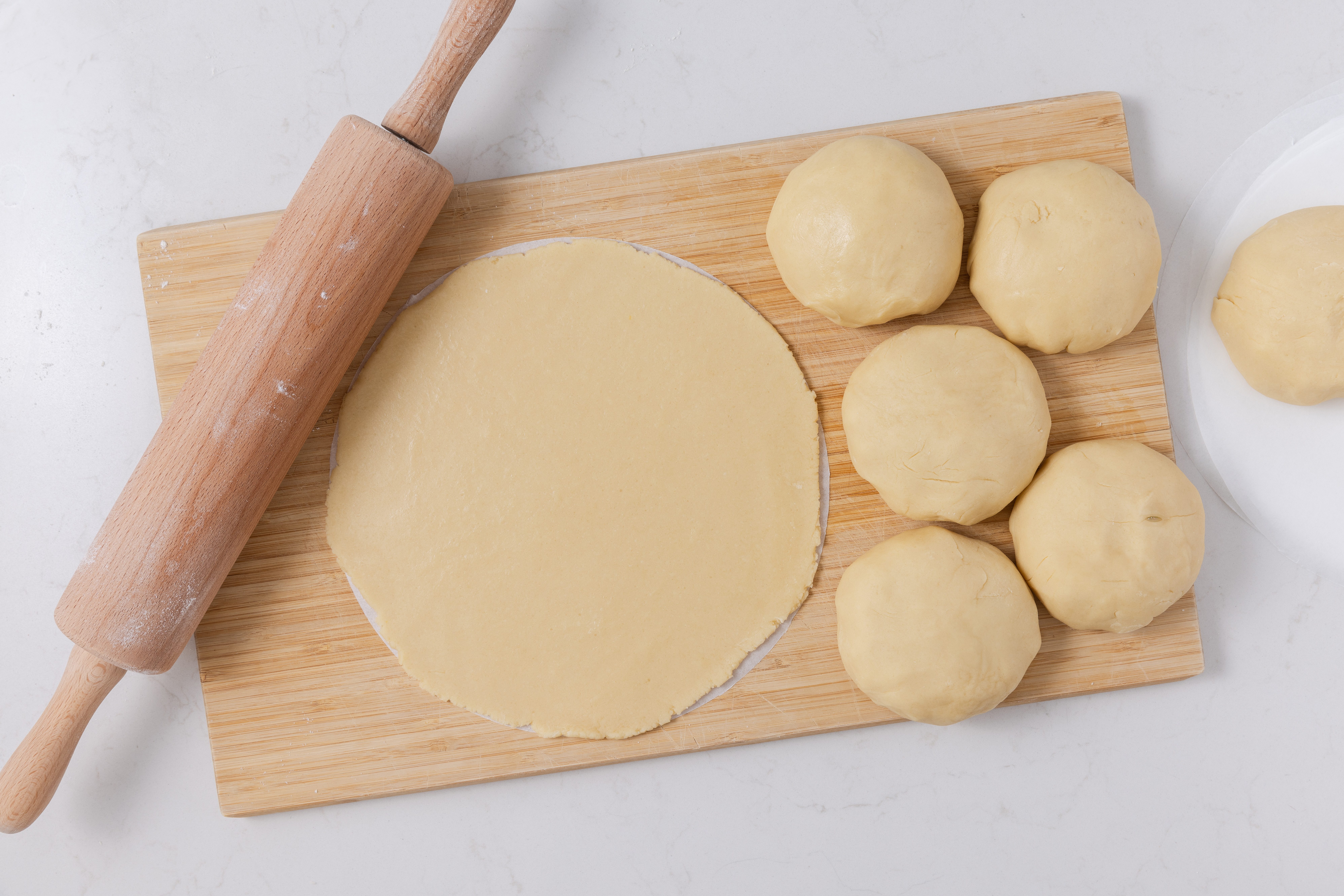 Cake dough being rolled out on parchment paper circles.