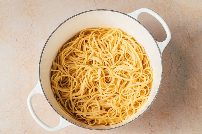 Cooked linguine pasta in a large pot for the Artichoke Tomato Pasta recipe by Taste of Home