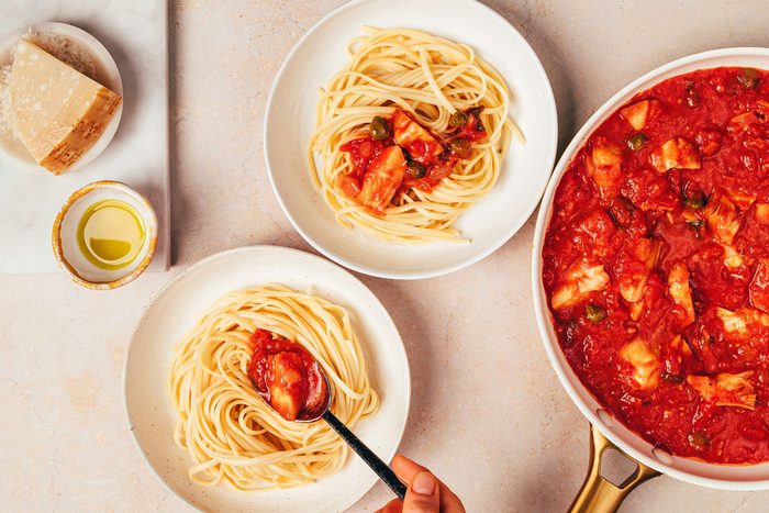 Combining cooked pasta with sauce to make the Artichoke Tomato Pasta recipe by Taste of Home