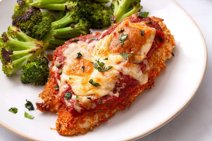 Baked Chicken Parmesan on a plate with a side of roasted broccoli florets for Taste of Home