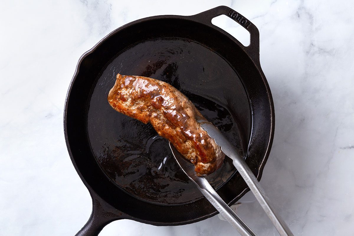 Pork tenderloin being coated in balsamic glaze for step four of Balsamic Pork Tenderloin recipe for Taste of Home