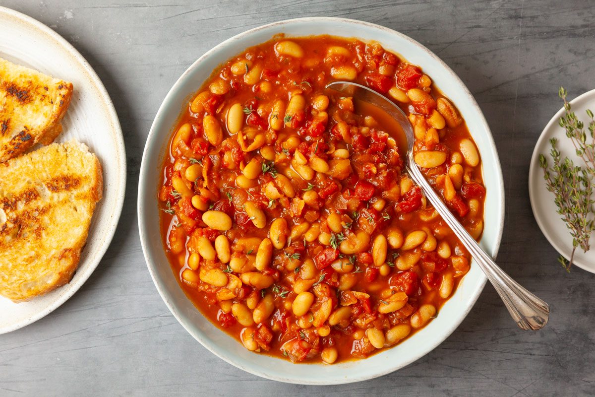 Full yield of Taste of Home British Baked Beans, toasted bread peaking in, topped with fresh thyme