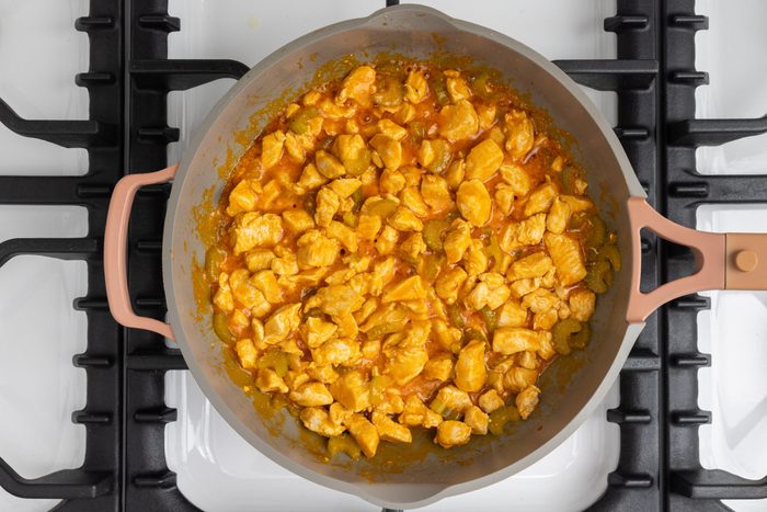 Buffalo chicken mixture being cooked in skillet.