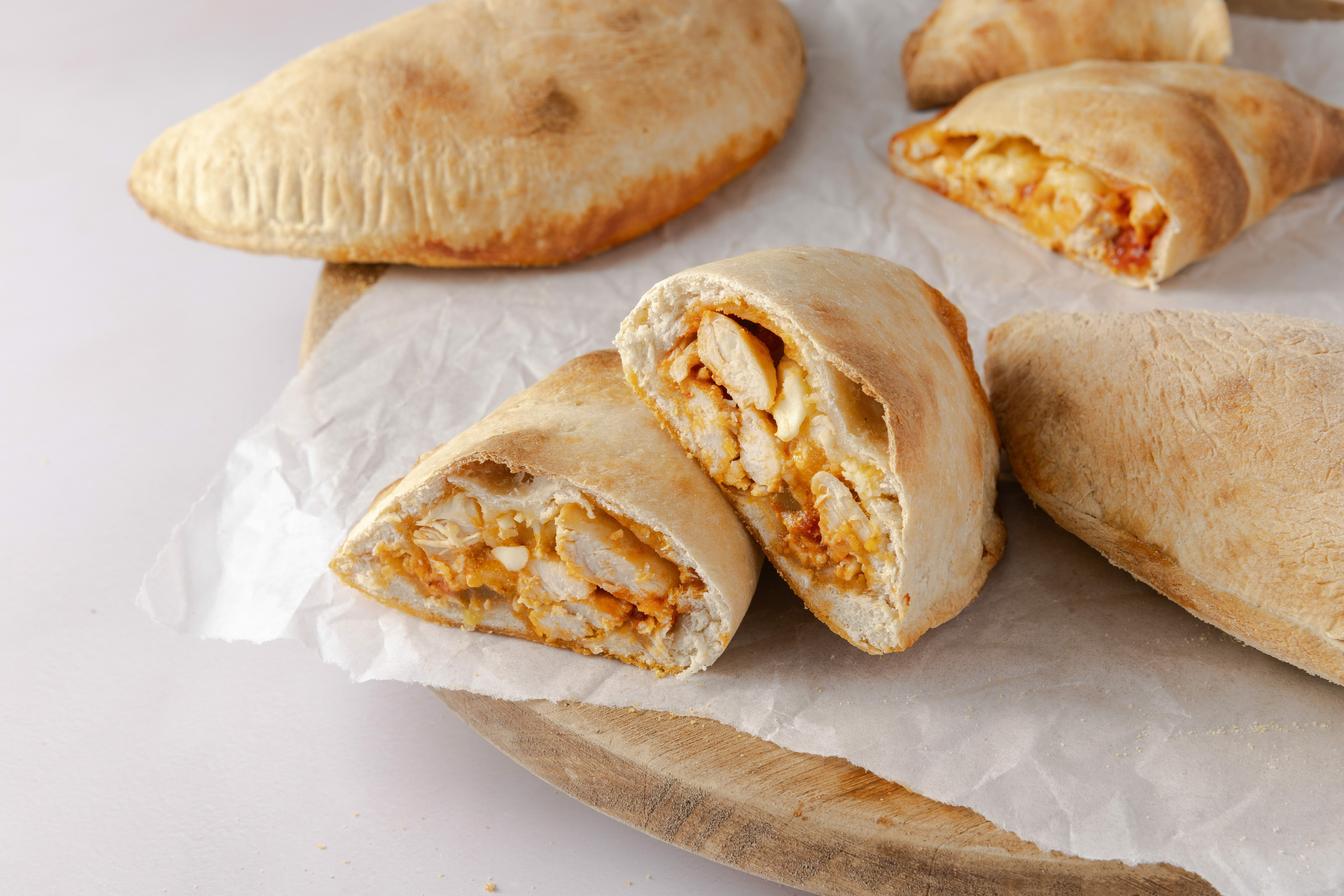 Calzones baked and cut in half on wood board.