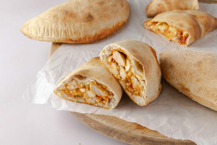 Calzones baked and cut in half on wood board.