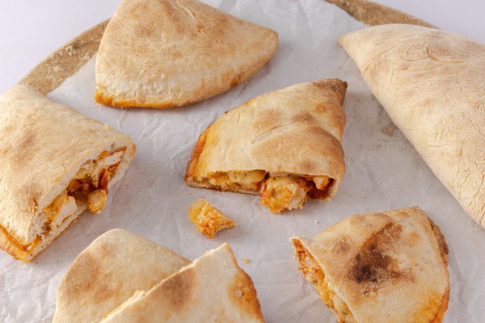 Calzones baked and cut in half on wood board.