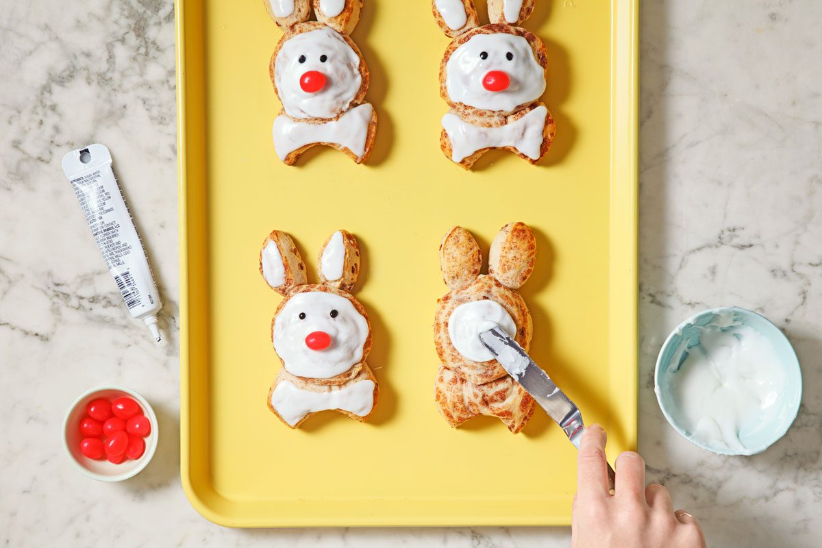 spreading icing over the bunnies and adding other decorations to make the faces