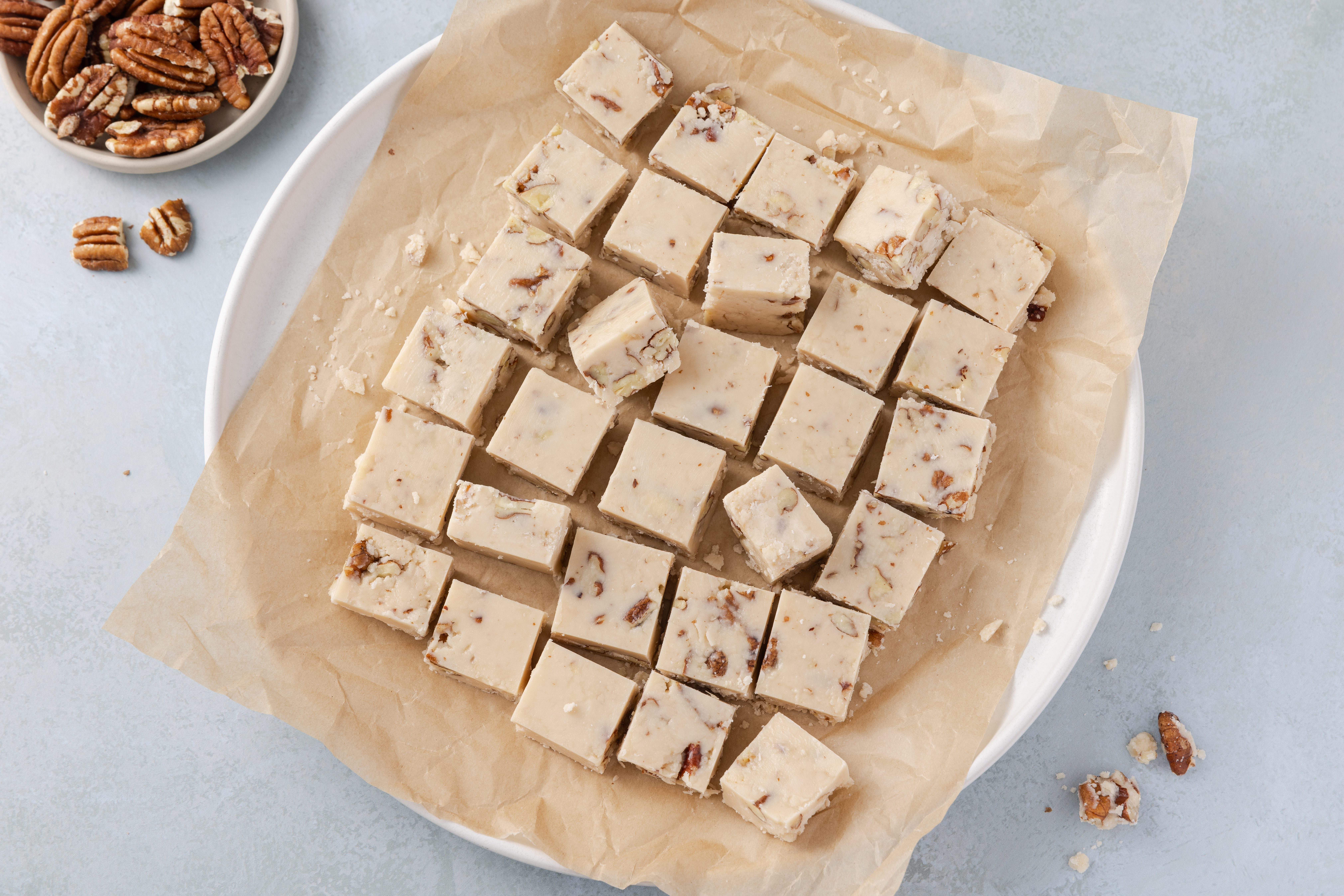 Butter pecan fudge ready and cut into 1 in squares, served on plate.