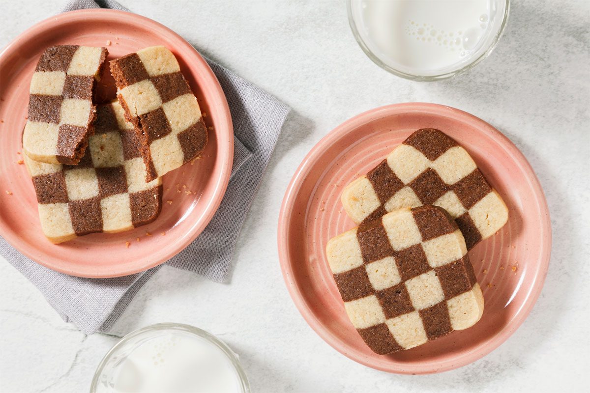 Checkboard Cookies served on pink plates with glasses of milk
