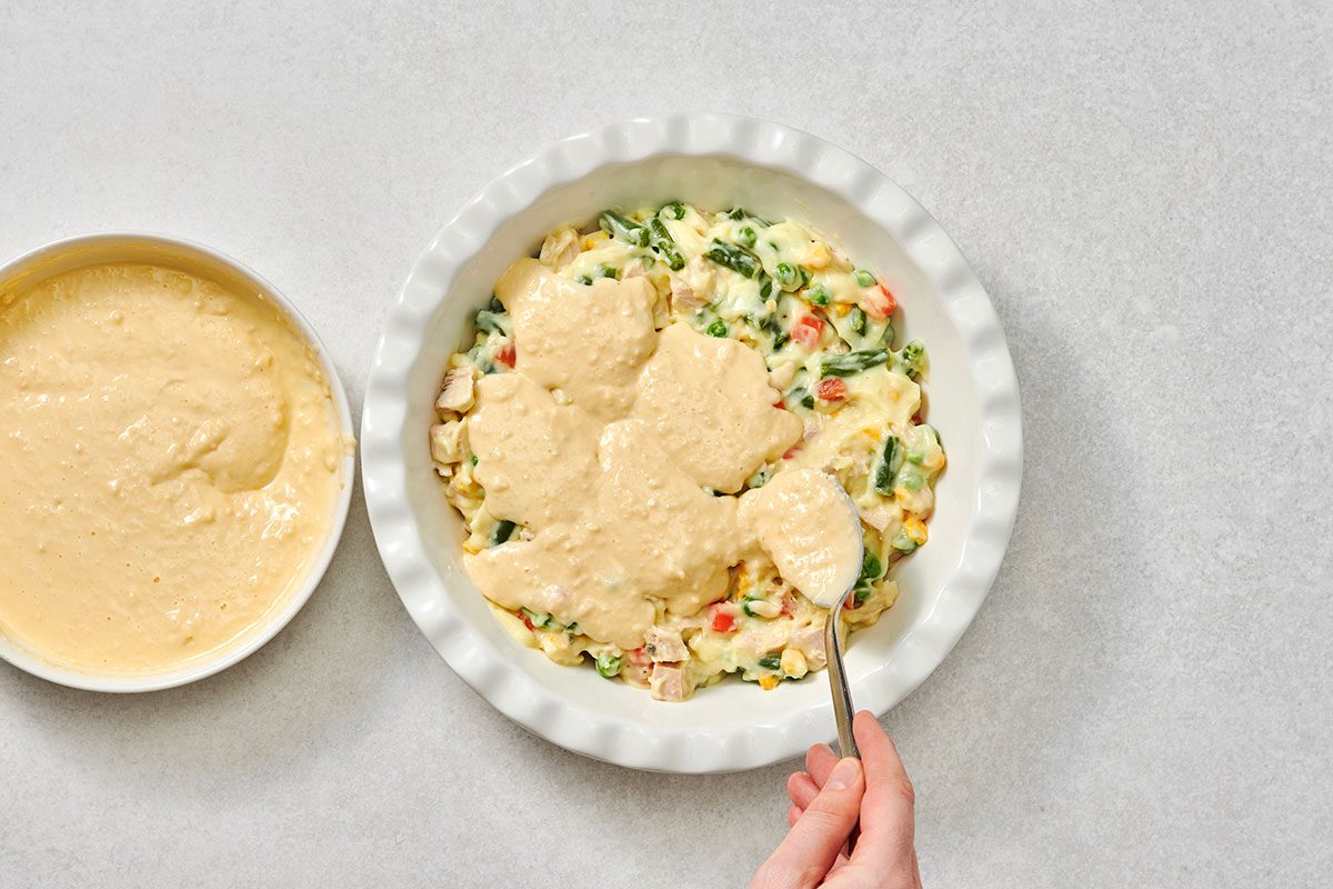 Spooning biscuit topping over the pie filling 