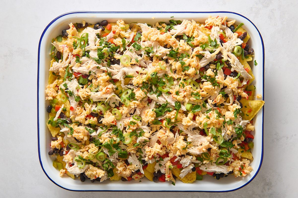 Nacho ingredients layered in a baking dish