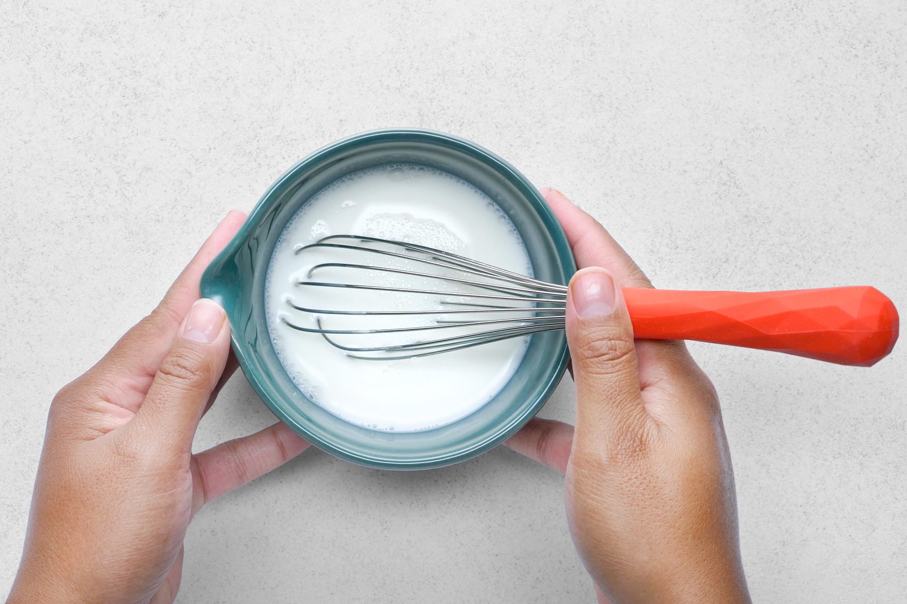 Cornstarch and milk are being mixed together until the mixture is smooth and free of lumps.