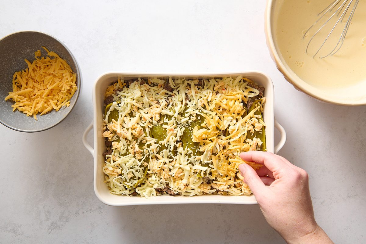 Sprinkling cheese over one of the layers of the casserole
