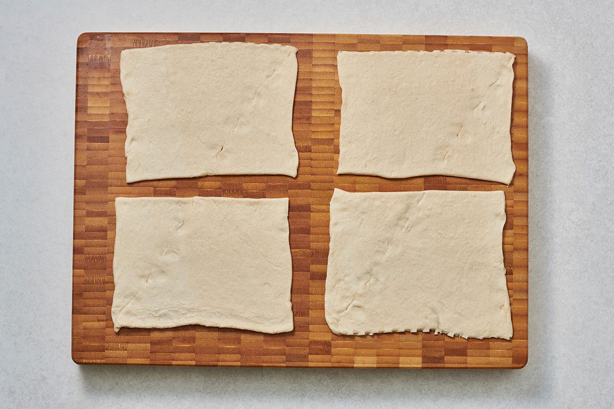 Crescent dough cut into 4 rectangles on a cutting board